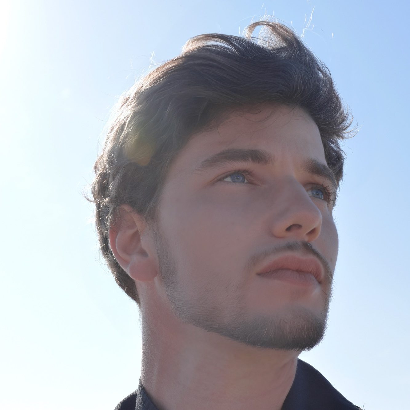 Homme sous les rayons du soleil avec un ciel bleu, illustrant la transformation et l’élévation spirituelle.